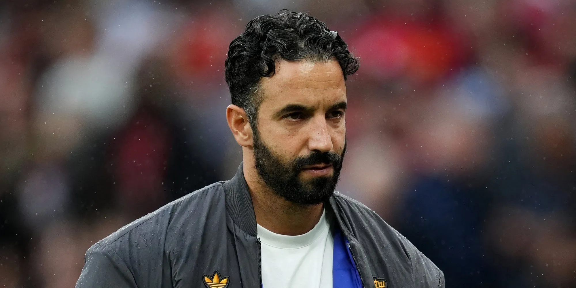 Ruben Amorim trên sân tập Man Utd, với logo câu lạc bộ phía sau, thể hiện sự tập trung vào chiến thuật